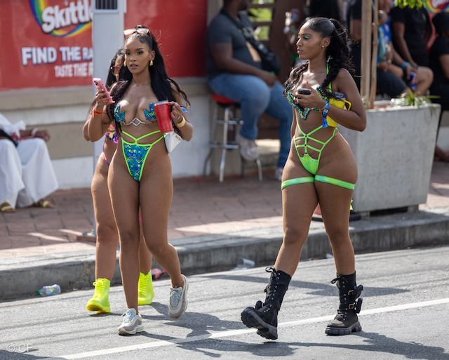 Two women in bikinis are walking down the street.