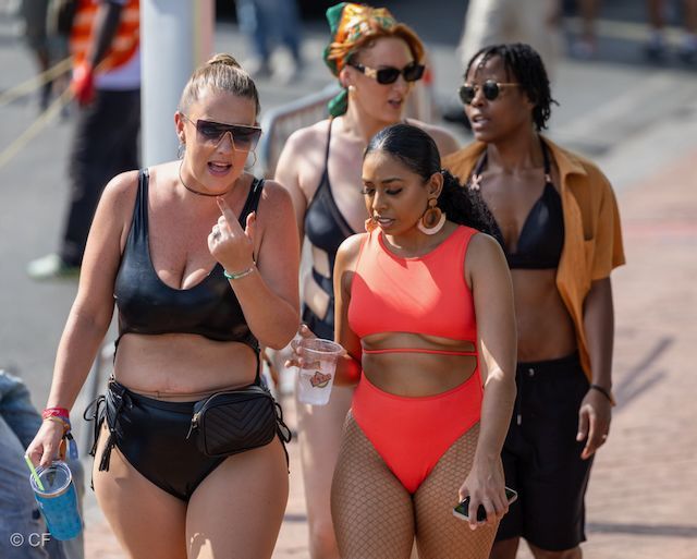 A group of women in bikinis are walking down the street.