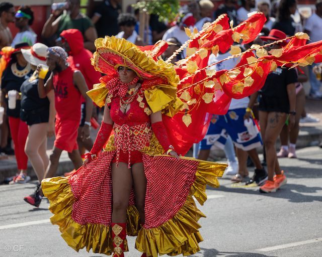 A woman in a red and yellow costume is walking down the street