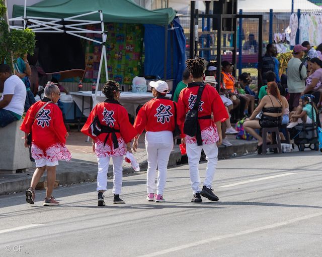 A group of people walking down a street wearing red shirts with chinese writing on them