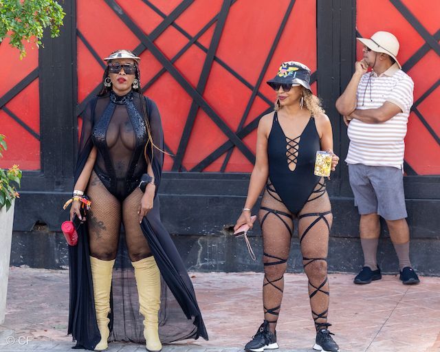 Two women standing next to each other in front of a red wall