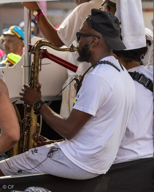 A man in a white shirt is playing a saxophone