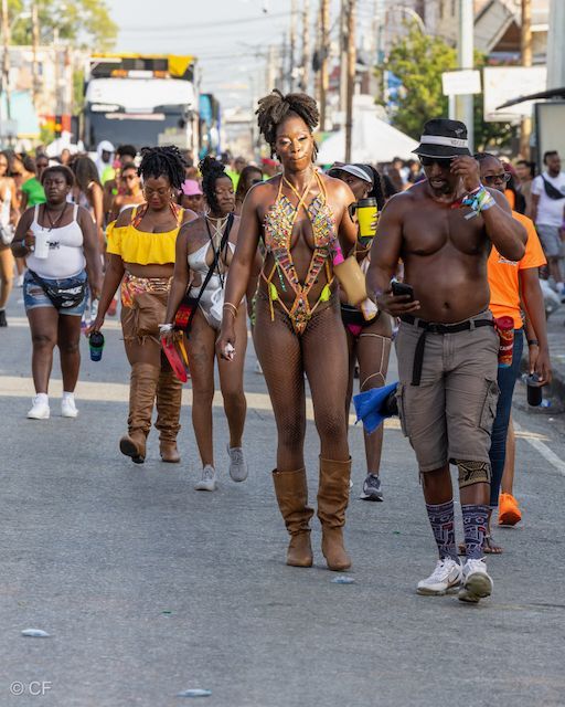 A group of people are walking down a street and one of them is wearing a swimsuit