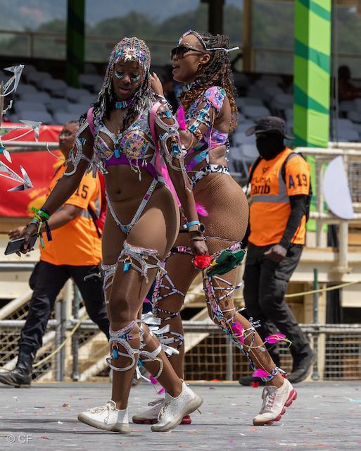 Two women in colorful costumes are walking in a parade.