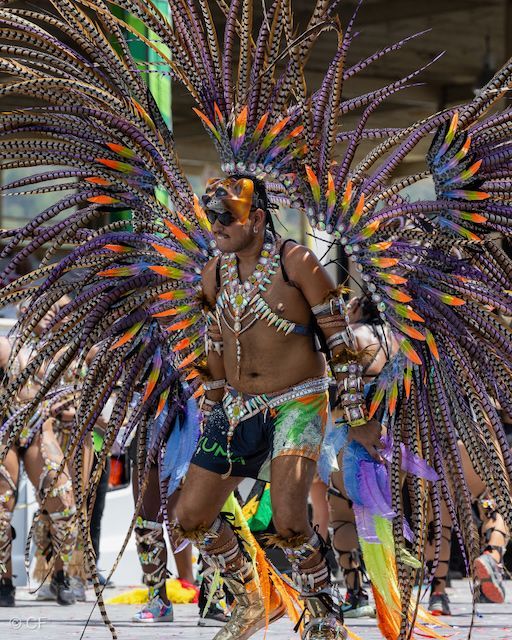 A man in a colorful costume is dancing in a parade.