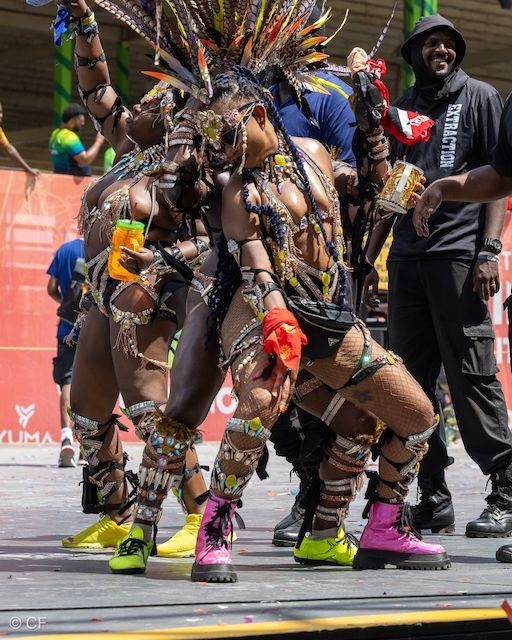 A group of people dressed in costumes are dancing in front of a red wall that says yuma