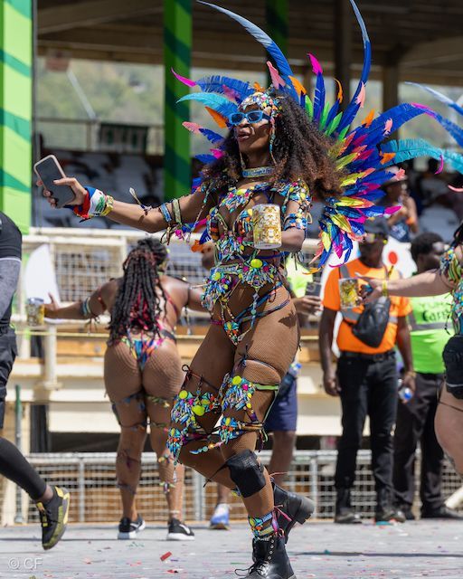 A woman in a colorful costume is dancing in a parade.