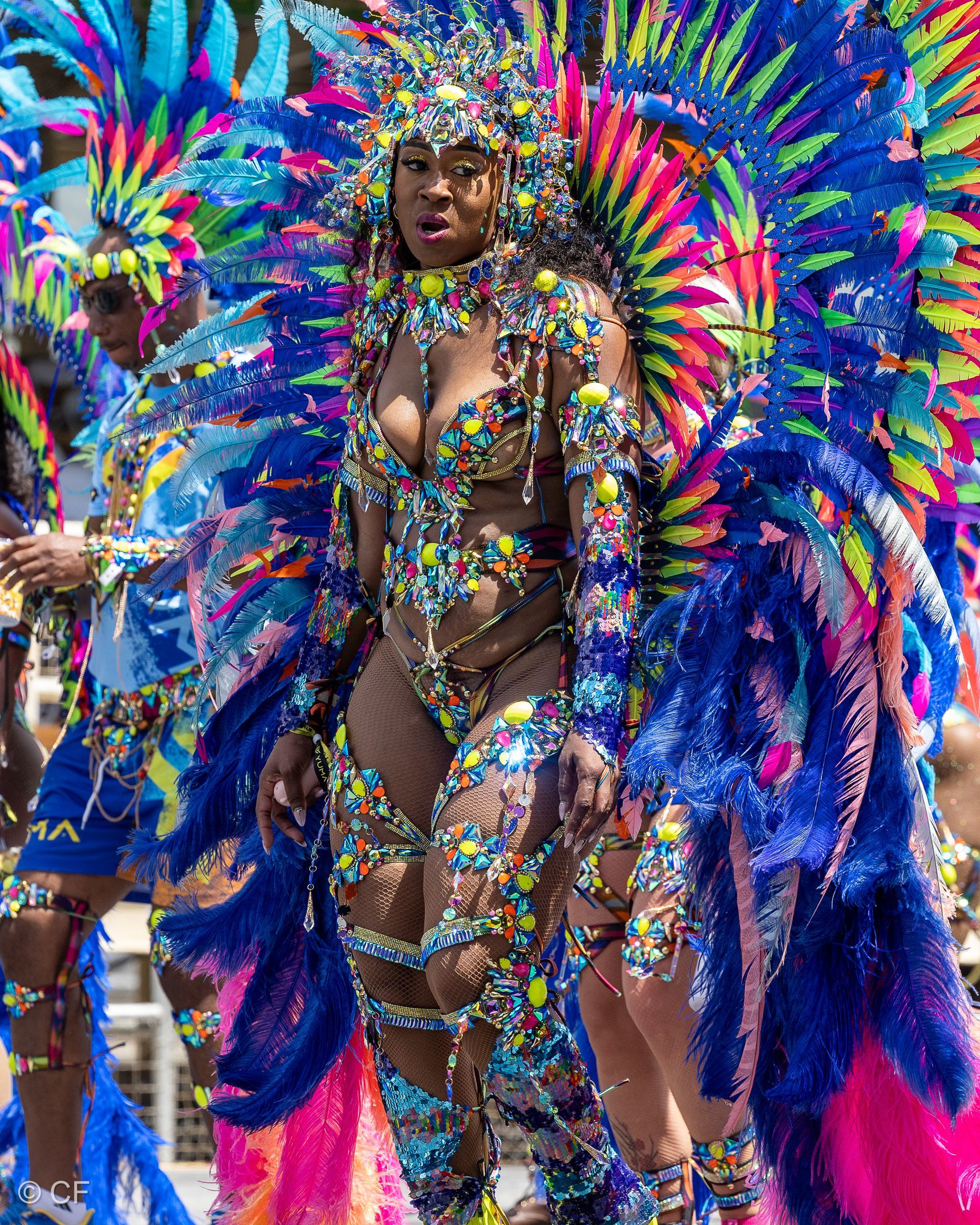 A woman in a colorful costume is walking in a parade.