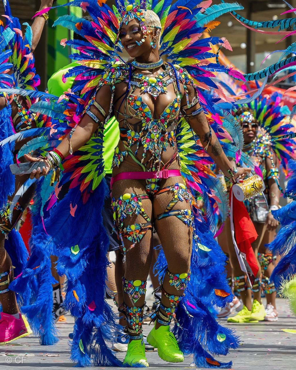 A woman in a colorful costume is dancing in a parade.