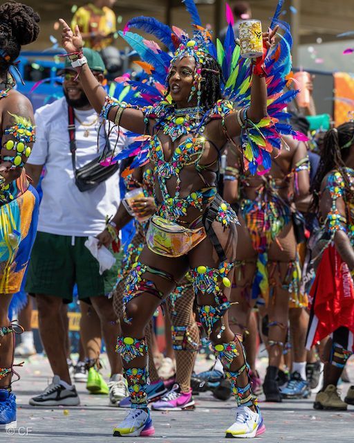 A woman in a colorful costume is dancing in a parade.