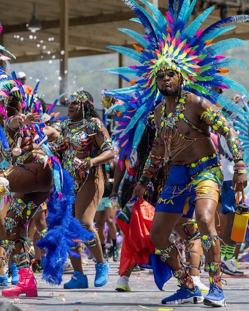 A man in a colorful costume is dancing in a parade.