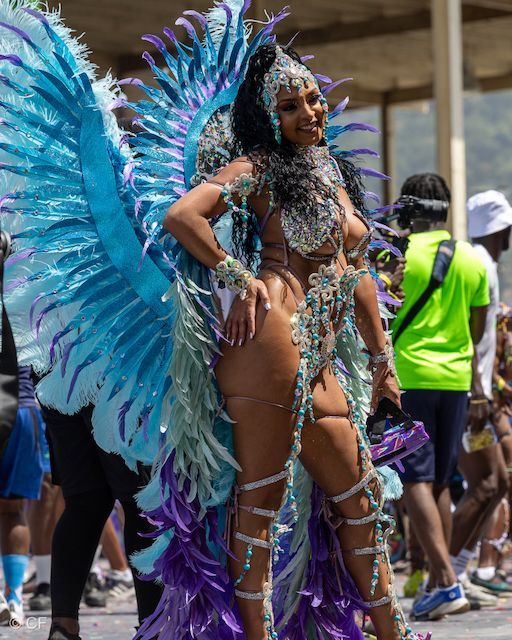 A woman in a colorful costume is standing in front of a crowd.