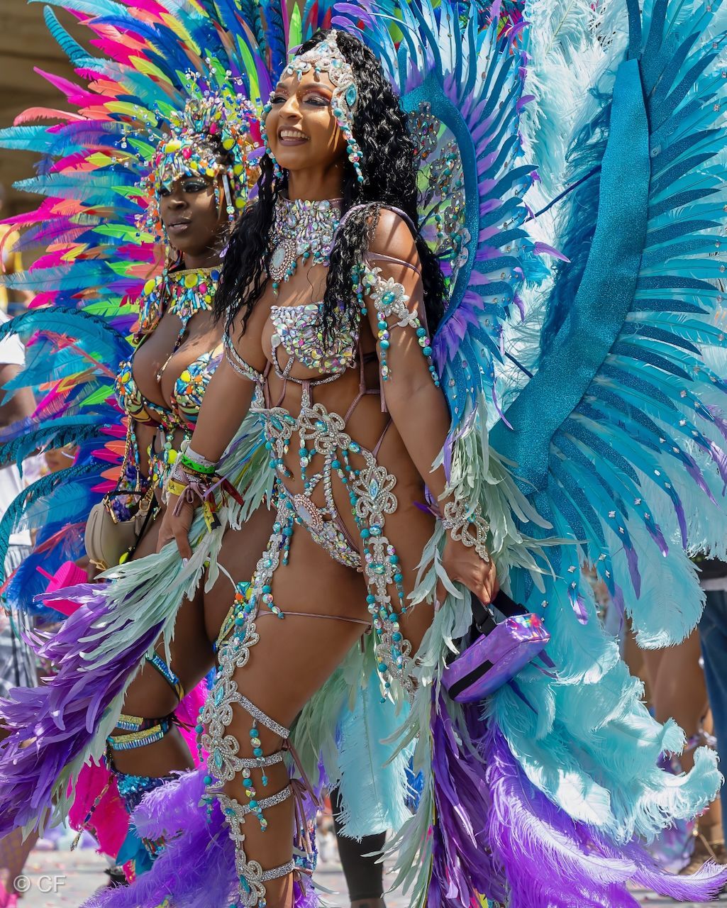 three women in colorful costumes are standing next to each other on a street .