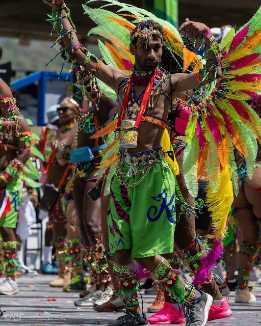 A man in a colorful costume is dancing in a parade.