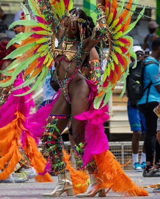 A woman in a colorful costume is dancing in a parade.