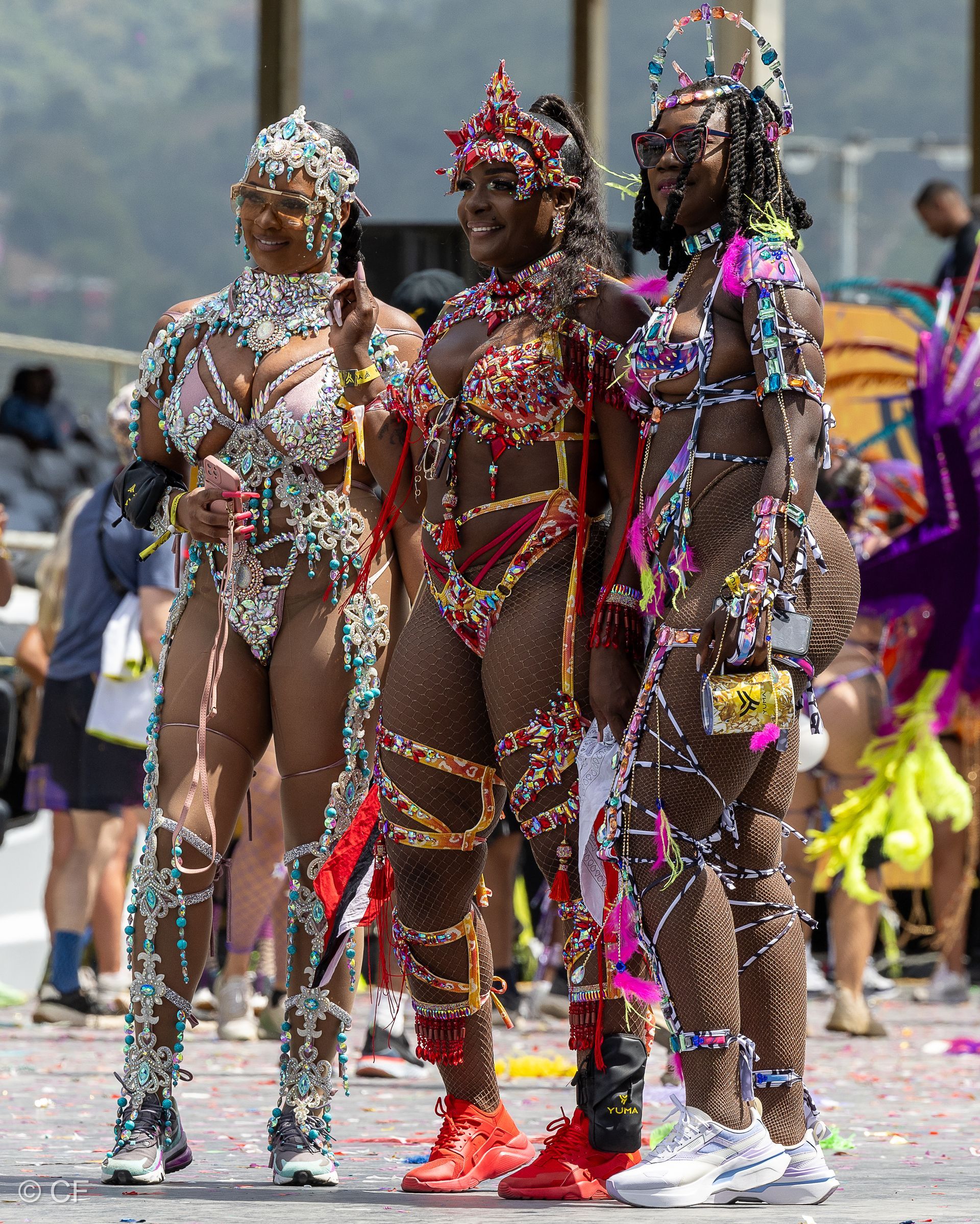 Three women in colorful costumes are standing next to each other on a street.