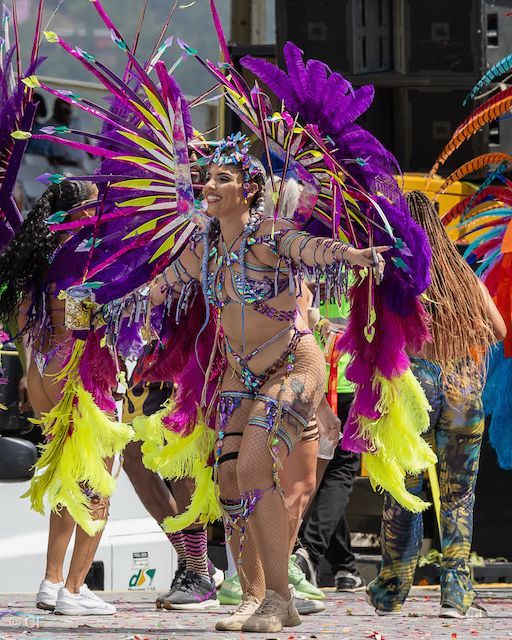 A woman in a colorful costume is dancing in a parade.