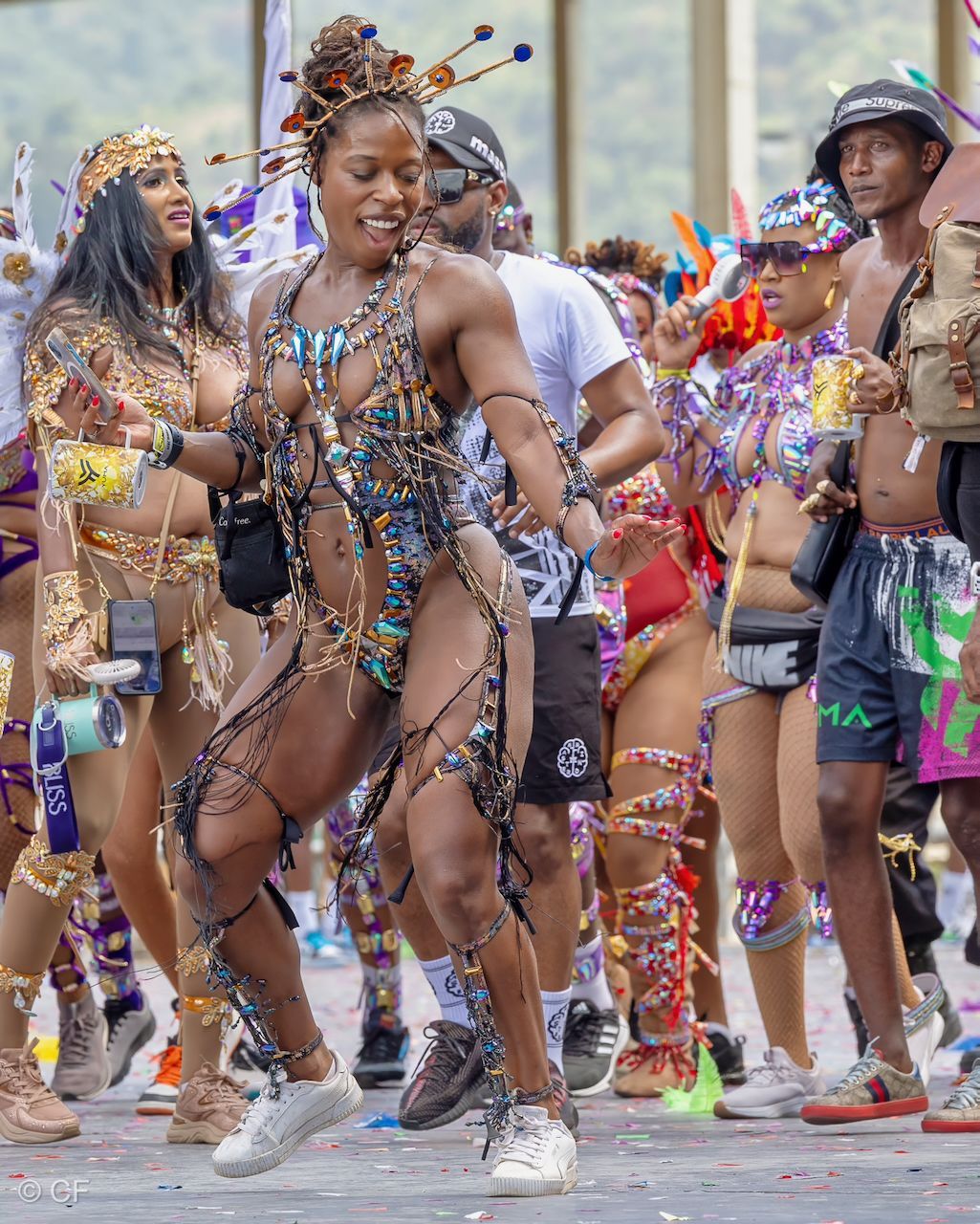 A woman in a colorful costume is dancing in a parade.