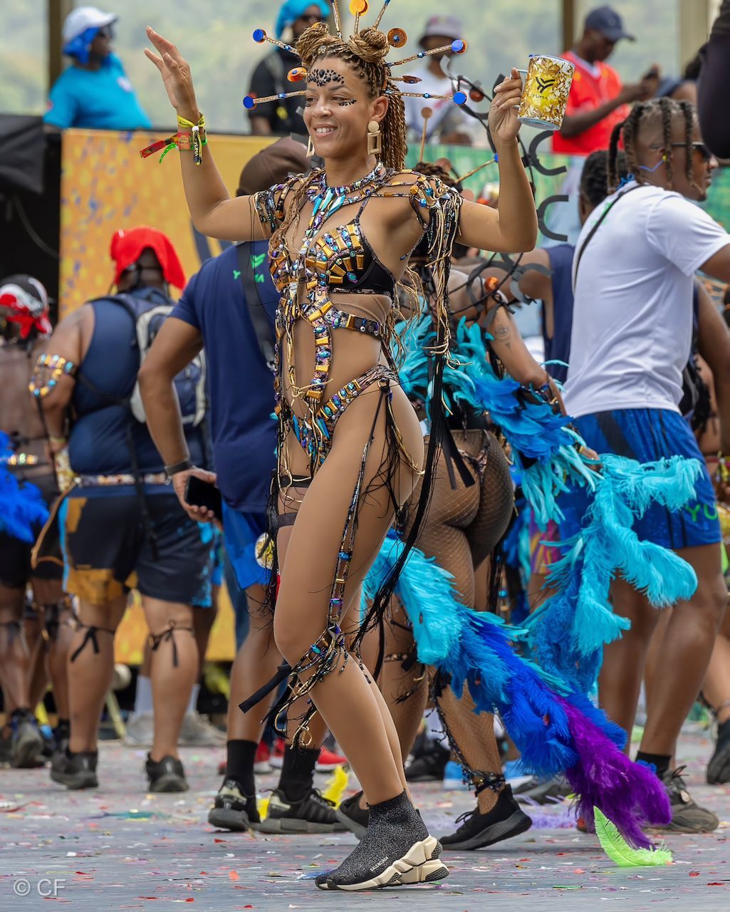 A woman in a carnival costume is dancing in front of a crowd
