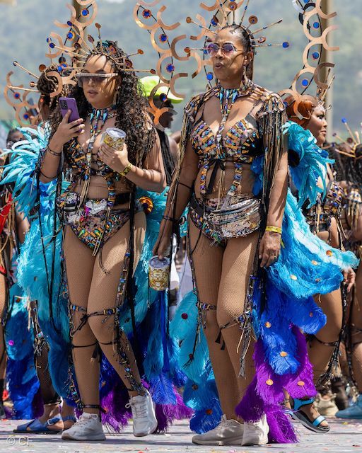 Two women in colorful costumes are walking down a street.
