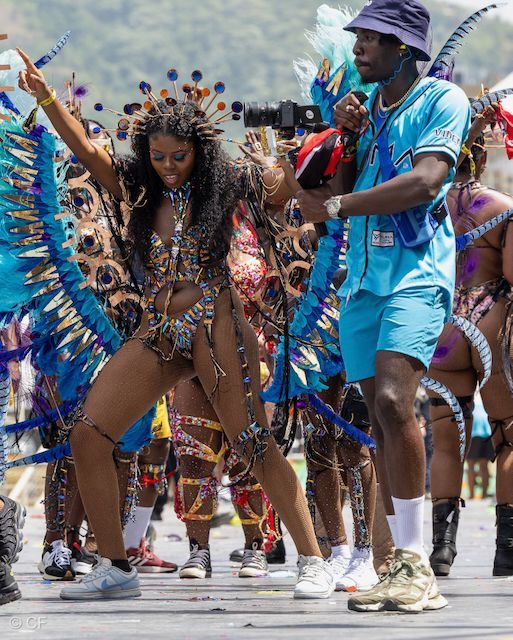 A man is taking a picture of a woman in a carnival costume.