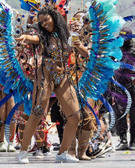 A woman in a colorful costume is dancing in a parade.