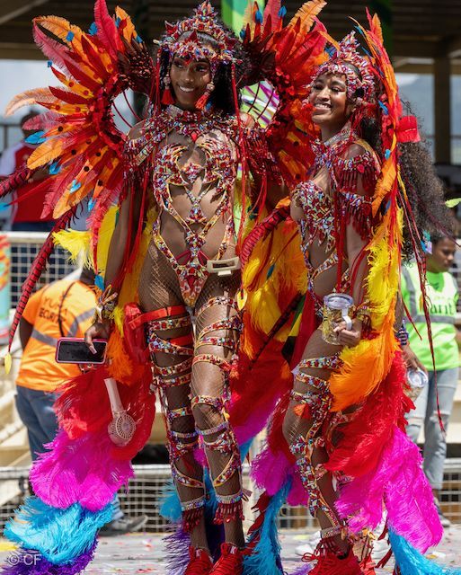 Two women in colorful costumes are standing next to each other at a carnival.