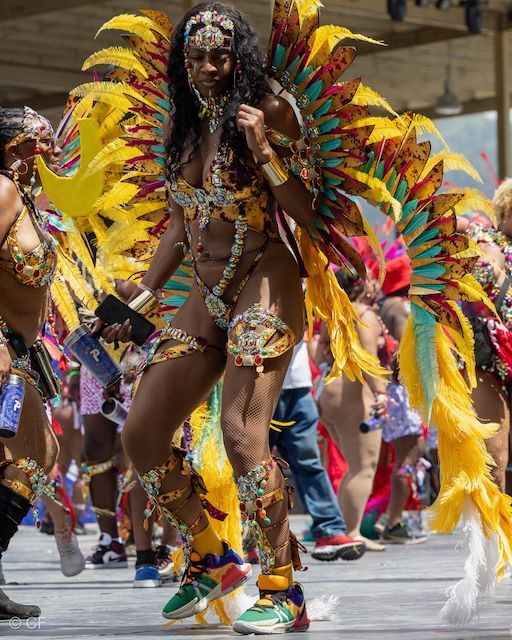 A woman in a colorful costume is dancing in a parade.