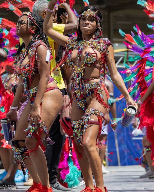 Two women in colorful costumes are dancing in a parade.