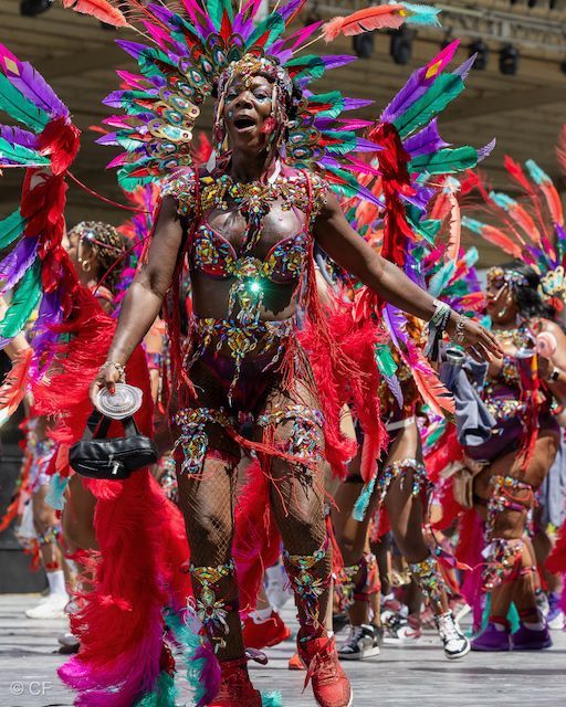 A woman in a colorful costume is dancing in a parade.