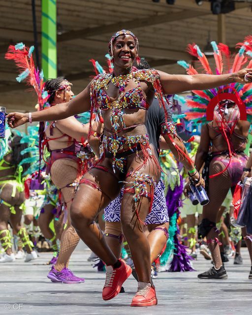 A woman in a colorful costume is dancing in a parade.