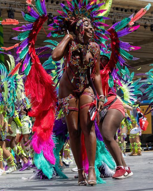 A woman in a colorful costume is dancing in a parade.