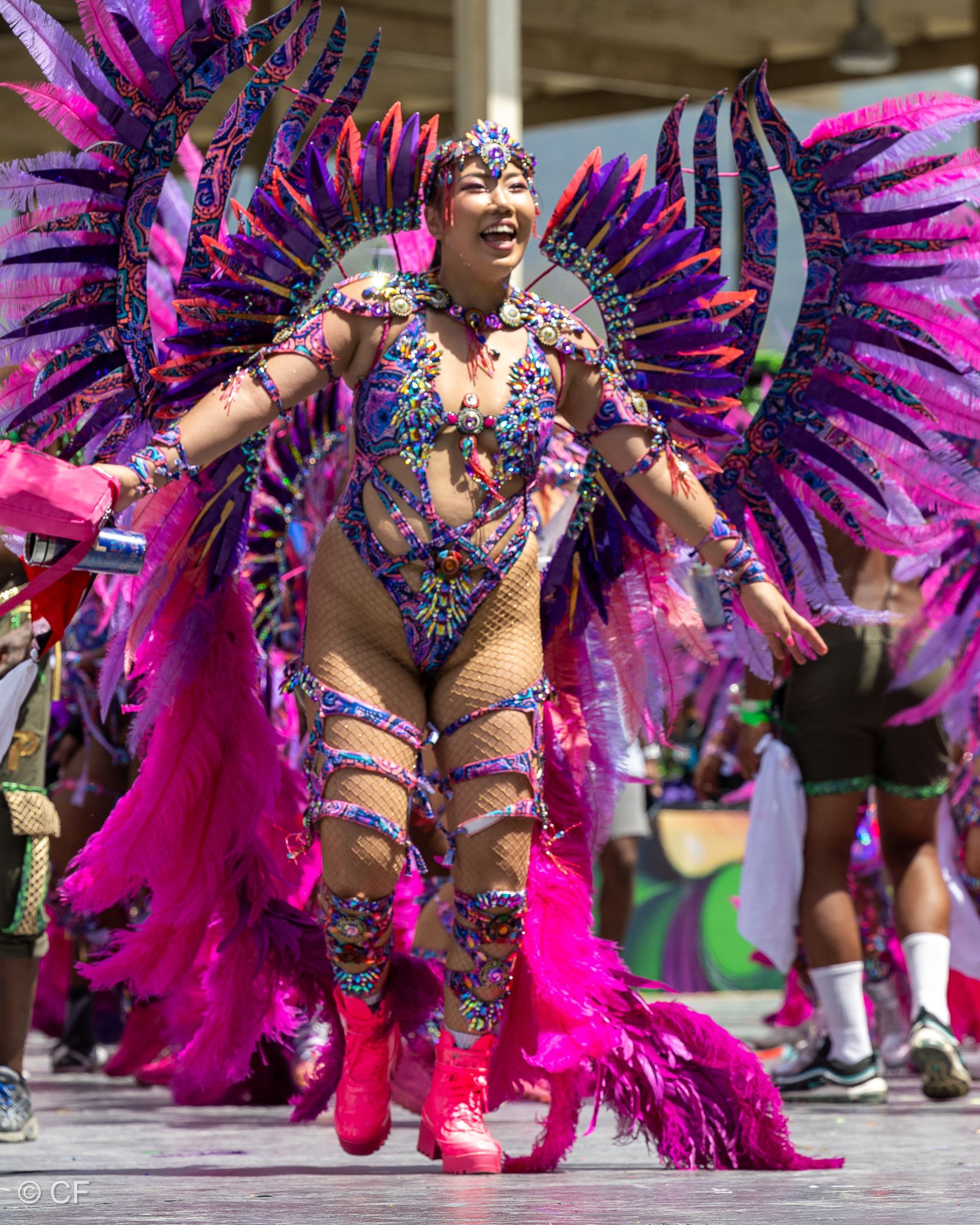 A woman in a colorful costume is dancing in a parade.
