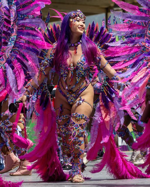 A woman in a colorful costume is dancing in a parade.