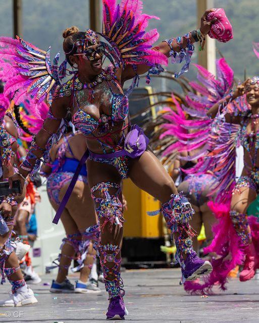 A woman in a colorful costume is dancing in a parade