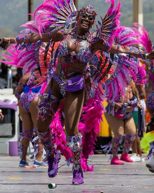 A woman in a colorful costume is dancing in a parade.
