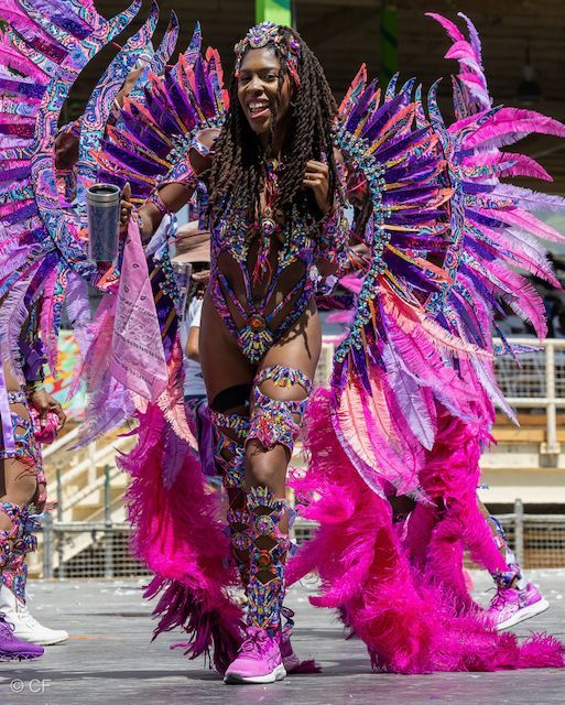 A woman in a colorful costume is dancing in a parade.