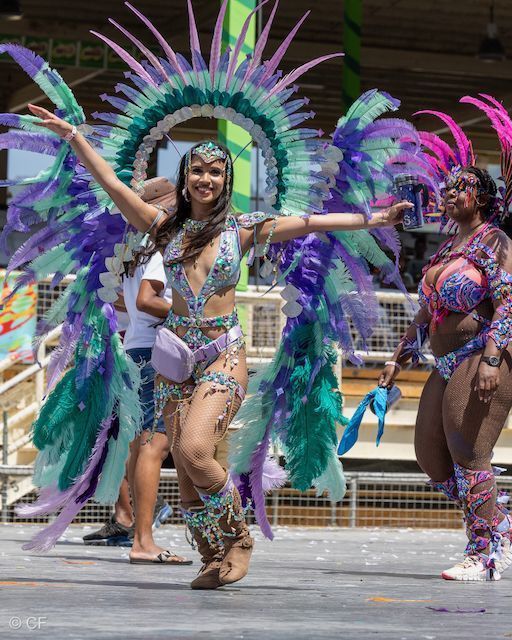 A woman in a colorful costume is dancing in a parade.