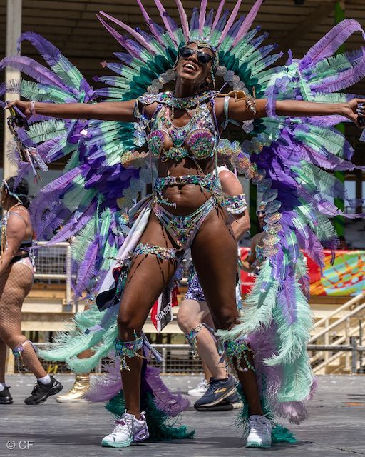 A woman in a colorful costume is dancing in a parade.