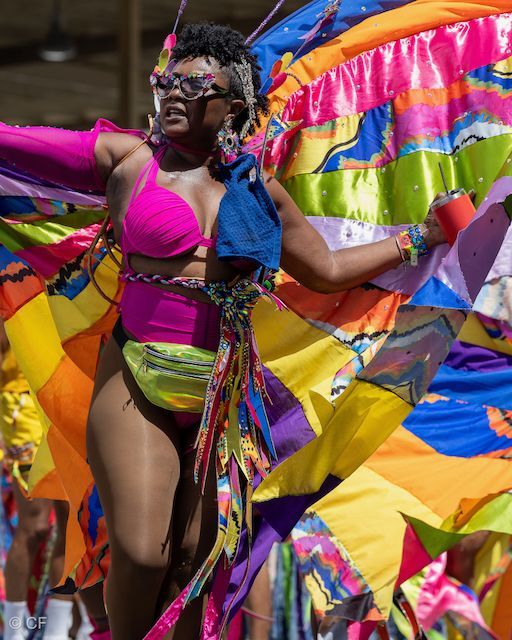A woman in a pink bikini is dancing in a colorful parade.
