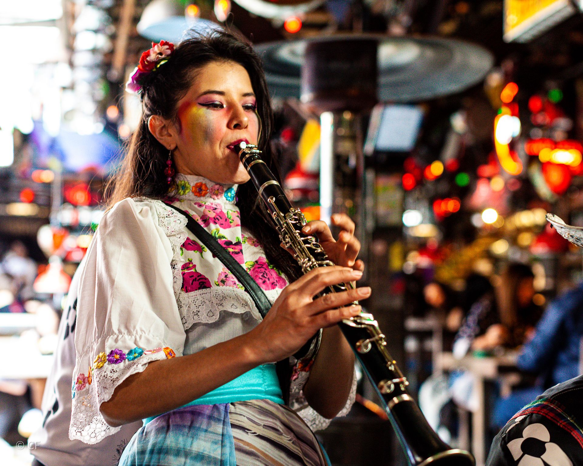 A woman in a colorful dress is playing a clarinet