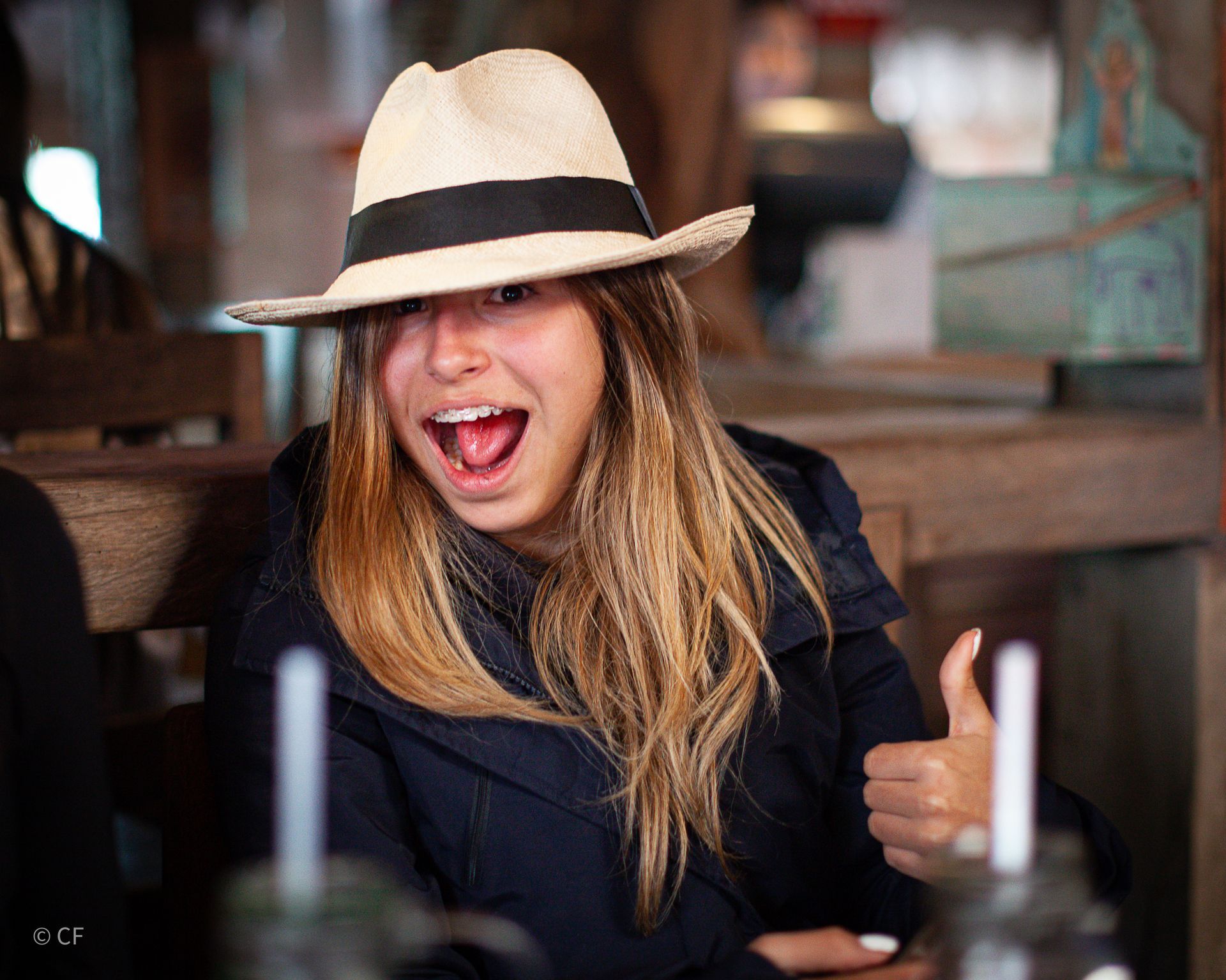 A woman wearing a hat is giving a thumbs up