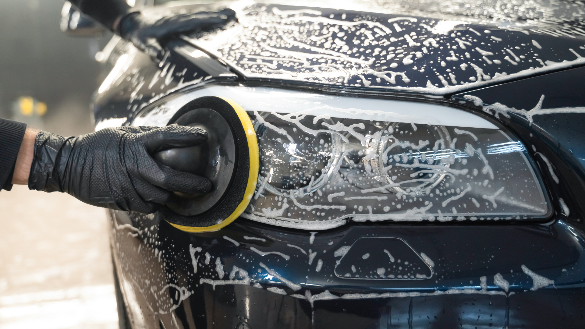 A person is polishing the headlight of a car.