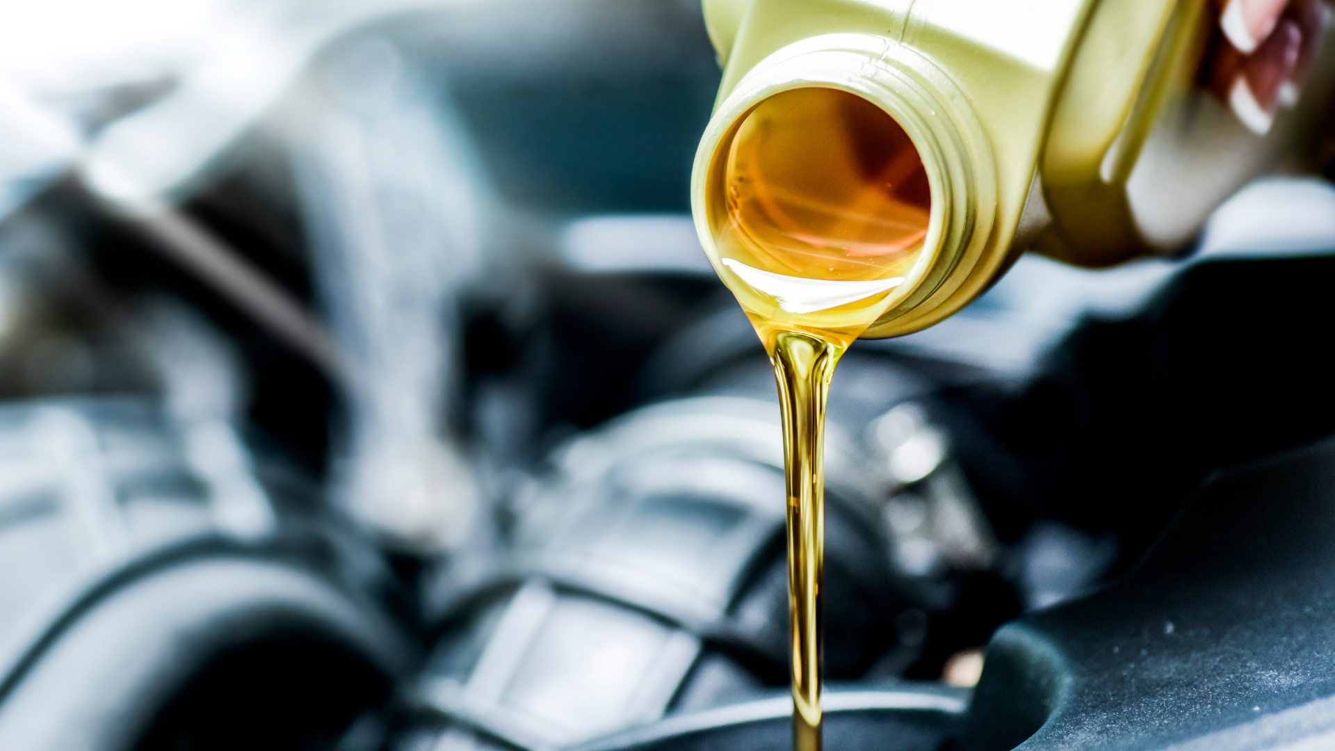 A person is pouring oil into a car engine.