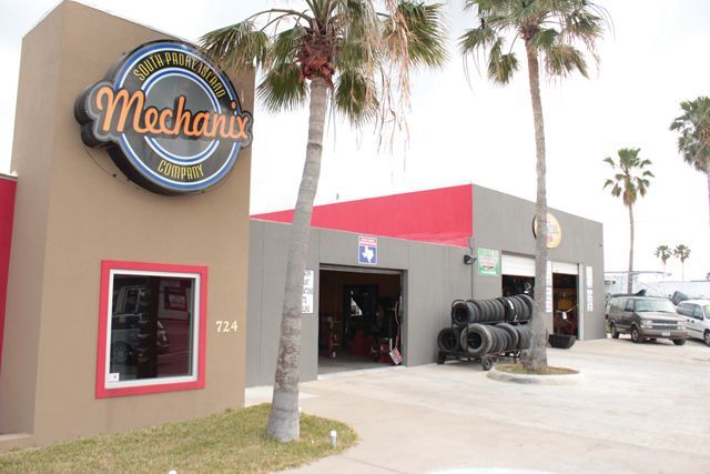 The outside of a mechanics shop with tires in the garage