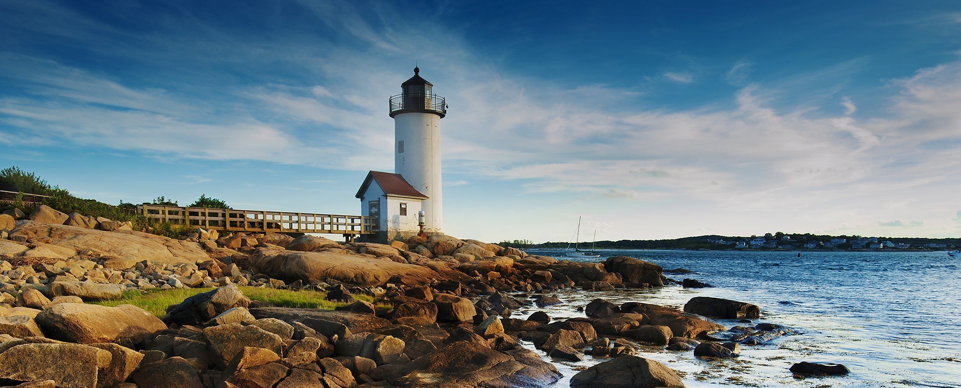 A lighthouse is sitting on top of a rocky shoreline next to the ocean.
