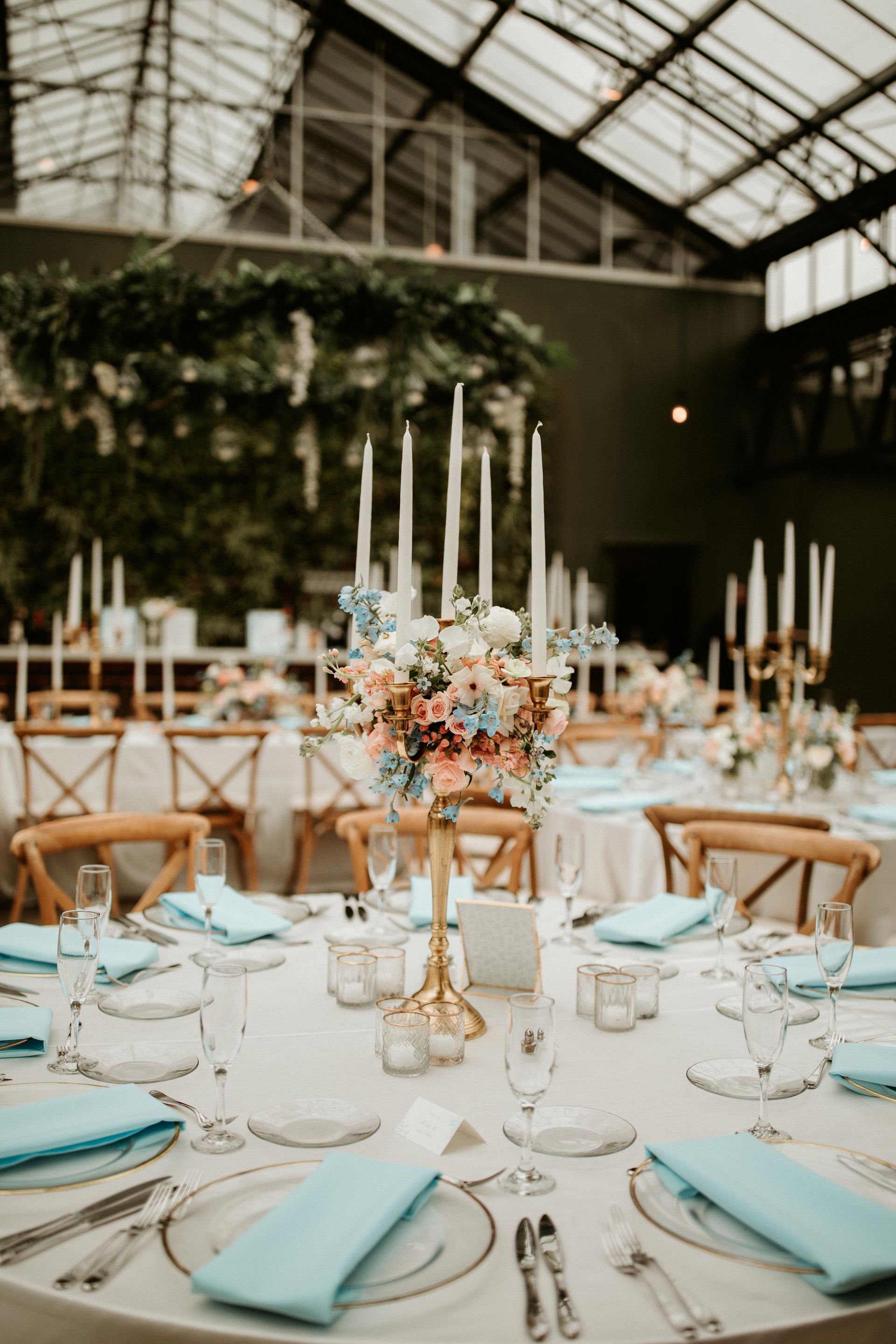 A table set for a wedding reception with candles and flowers on it.