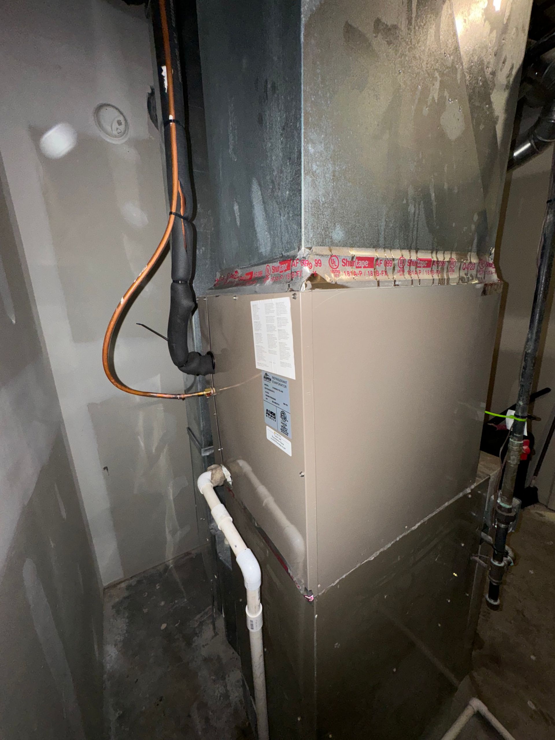 A picture of a furnace in a room with pipes coming out of it.