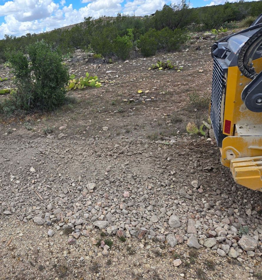 A yellow truck is parked on the side of a dirt road.