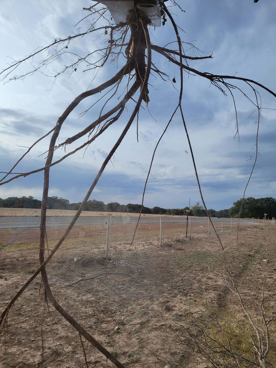 A bunch of wires are hanging from a pole in a field